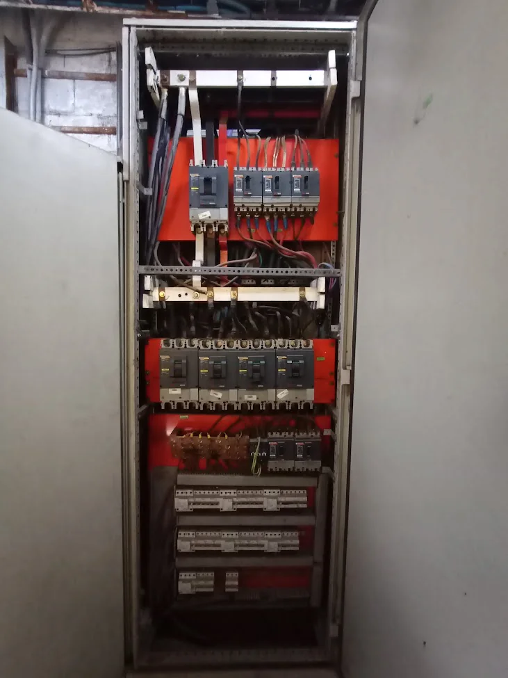 Tablero eléctrico abierto con interruptores, cableado y componentes montados en su interior.